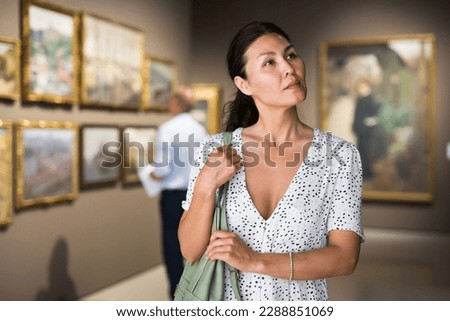 Asian woman admiring art work in museum