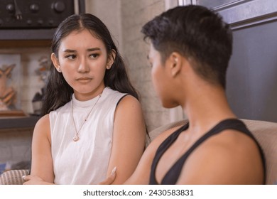 An Asian woman appears worried as she gazes at her boyfriend, capturing a moment of relationship tension. - Powered by Shutterstock