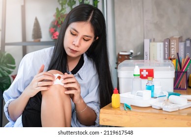 Asian Woman Applying Antiseptic Solution To Wound On Her Knee With First Aid Kit At Home