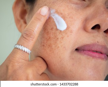 Asian woman are applying cream for facial treatment problem spot melasma pigmentation skincare on her face.  - Shutterstock ID 1433702288