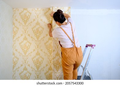 Asian Woman Applying New Wallpaper At Home. Renovate And House Decoration.