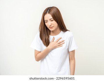 Asian woman around 25 year She felt a pain in her chest held her hand and squeezed it. She had a heart attack that needed treatment. Wearing white shirt standing on isolated background. - Powered by Shutterstock