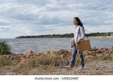 Asian woman artist looking for inspiration. Beautiful smiling Korean girl holding canvas, paint brush, easel, enjoying beautiful landscape. Portrait of happy successful painter walking along beach  - Powered by Shutterstock