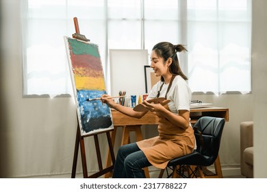 Asian woman artist working on painting with brush and variant acrylic color. Female artist painter on canvas in creative studio as art concept - Powered by Shutterstock