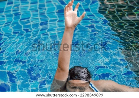 Asian woman asking for help is drowning due to leg cramp in swimming pool