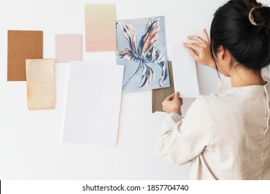 Asian woman attaching a plain white paper to a wall - Powered by Shutterstock