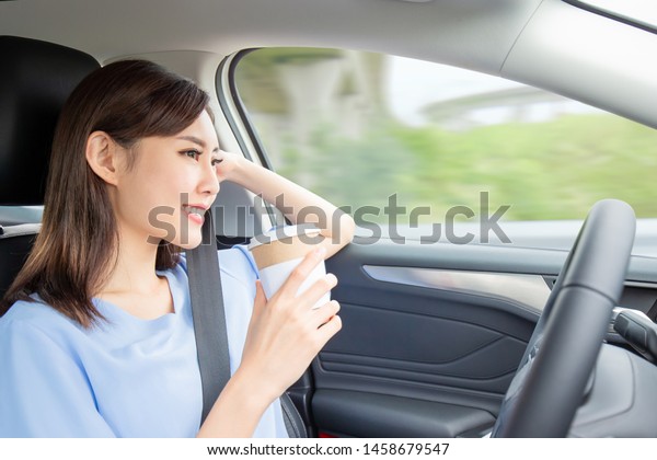 Asian woman in an autonomous self driving car and
drink a coffee on the
highway