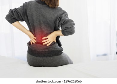 Asian woman back pain and sit on bed in bedroom in the morning.color tone - Shutterstock ID 1296262066