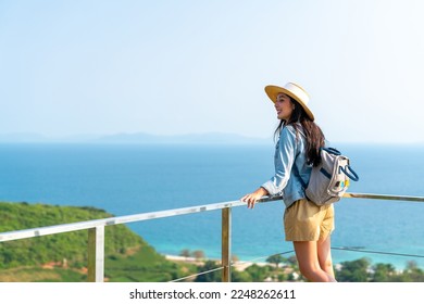 Asian woman with backpack solo travel on tropical island mountain peak in summer sunny day. Attractive girl enjoy and fun outdoor lifestyle looking beautiful nature of ocean on beach holiday vacation. - Shutterstock ID 2248262611