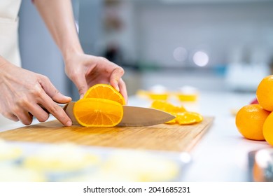 Asian Woman Bakery Shop Owner Preparing Bakery In The Kitchen. Adult Female Using Kitchen Knife Cut Fresh Fruit For Making Fruit Tart. Small Business Entrepreneur And Indoor Lifestyle Baking Concept.