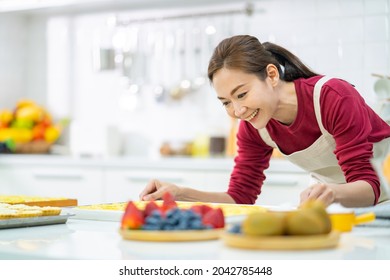 Asian Woman Bakery Shop Owner Preparing Bakery In The Kitchen. Female Baker Baking Tart Dough For Making Fruit Tart On The Table. Small Business Entrepreneur And Indoor Activity Lifestyle Concept.