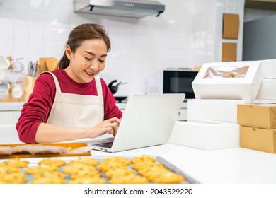 Asian woman bakery shop owner using laptop computer with internet presentation dessert bakery on social media in the kitchen. Small business entrepreneur and online marketing food delivery concept - Powered by Shutterstock