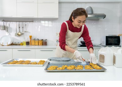 Asian woman bakery shop owner preparing customer order cookie in delivery box on kitchen counter. Woman bakery chef making bakery in the kitchen. Small business entrepreneur and food delivery concept. - Powered by Shutterstock