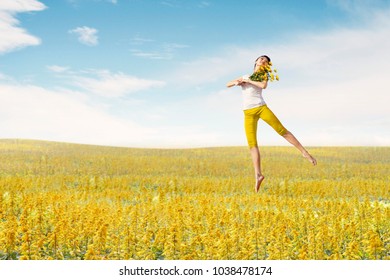 Asian woman ballerina holds bouquet of flowers making a big jump on meadow. Summer or Spring concept