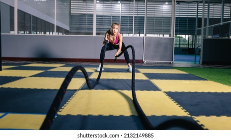 Asian Woman With Battle Ropes Exercise In The Fitness Gym. Wide Angle Shot 
