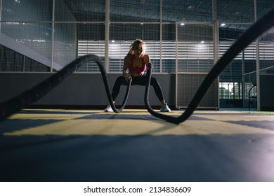 Asian Woman With Battle Ropes Exercise In The Fitness Gym. Wide Angle Shot 
