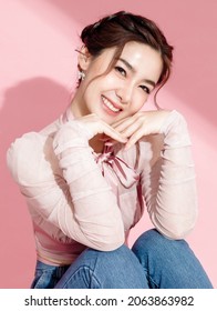Asian woman with a beautiful face and fresh, smooth skin is dressed in pink. Cute female model with natural makeup and sparkling eyes is smiling and looking at the camera on pink isolated background. - Shutterstock ID 2063863982