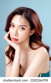 Asian Woman With A Beautiful Face And Perfect Clean Fresh Skin. Cute Female Model With Natural Makeup And Sparkling Eyes On Blue Isolated Background. Facial Treatment, Cosmetology, Beauty Concept.