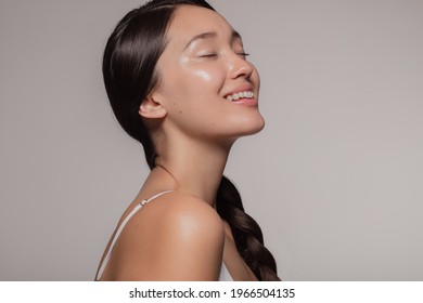 Asian woman with beautiful and healthy skin on beige background. Girl smiling with her eyes closed. - Shutterstock ID 1966504135