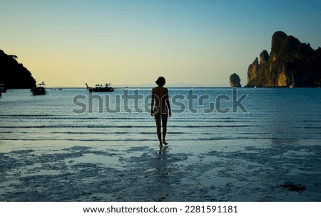 Asian woman in bikini entering the water at Thailand's Koh Phi Phi beach in the evening