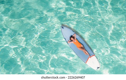 Asian woman in bikini sleep and relax on paddle board on the beach in summer time - Powered by Shutterstock