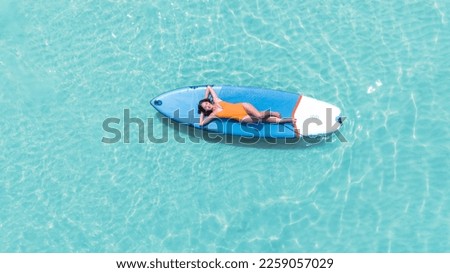Asian woman in bikini sleep and relax on paddle board on the beach in summer time at Pattaya beach, Thailand