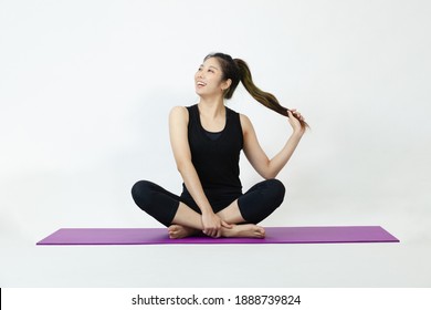 Asian Woman In Black Sportswear Sitting On Purple Yoga Mat Yoga Pose On The White Background.