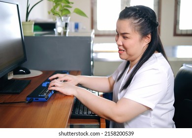 Asian woman with blindness disability using computer with refreshable braille display or braille terminal a technology assistive device for persons with visual impairment in workplace. - Shutterstock ID 2158200539