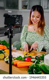 Asian woman blogger or content creator cooking and recording video camera. showing healthy food while recording with camera at kitchen.