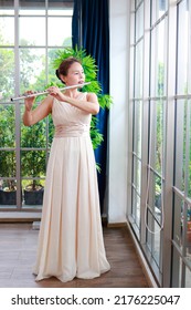 Asian Woman Blowing The Flute, A Universal Classical Instrument. The Concept Of A Classical Music School. Music Teacher