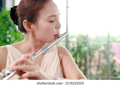 Asian Woman Blowing The Flute, A Universal Classical Instrument. The Concept Of A Classical Music School. Music Teacher