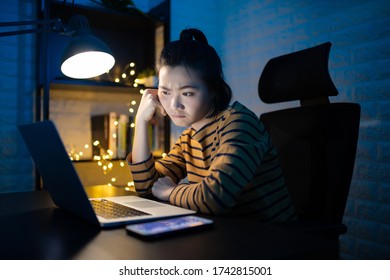 Asian Woman Bored Working On A Laptop Overtime At Home. WFH. Work From Home For Avoid The Coronavirus COVID 19 Concept.