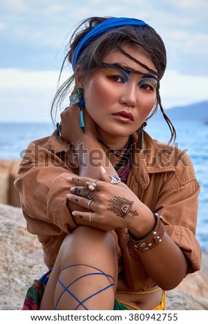 Asian woman, bright makeup, boho style, ethnic fashion, near sea. 