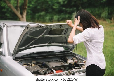 Asian Woman With A Broken Car With Open Hood.