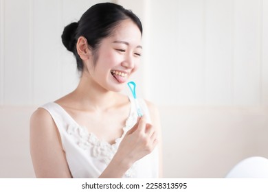 Asian woman brushing her tongue