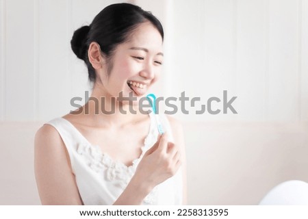Asian woman brushing her tongue