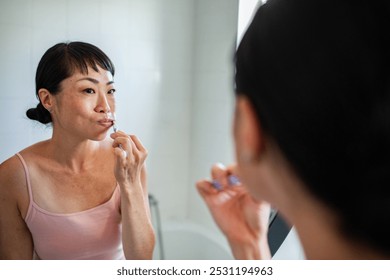 Asian woman brushing teeth in the bathroom - Powered by Shutterstock