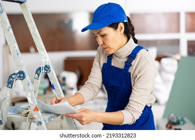 Asian Woman Builder Filling Project Documentation While Working In Apartment.