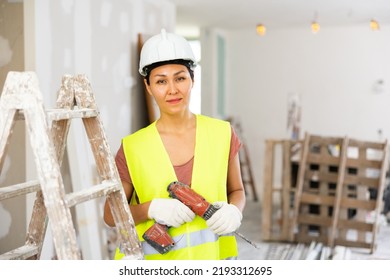 Asian Woman Builder Holding Drill, Smiling And Looking At Camera. Repair Works In House.