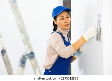 Asian Woman Builder Using Floated Trowel To Daub Plaster To Wall.