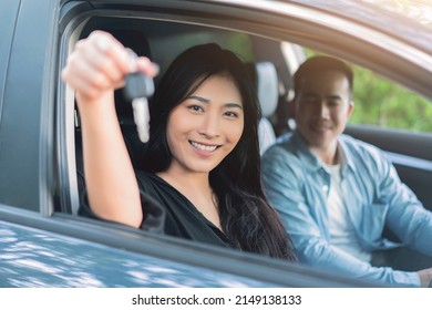 Asian Woman Buying Or Renting Rental New Car Owner Car Key Hand Shake From Sales Seller, Taking And Passing Driving License Examination Test Happy Cheerful Smiling Excited Salesman Sold Car Dealership