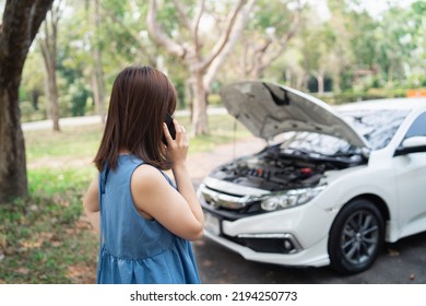 Asian woman calling garage after car breaks down. woman opening car hood and call to insurance or someone to help after the car breaks down, park on the side of the road. Transportation concept. - Powered by Shutterstock