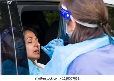 Asian woman in a car having a coronavirus nasal swab test with a nurse in PPE gear. England, UK - Shutterstock ID 1828307852