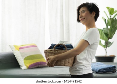 An Asian Woman Carry A Weaving Bamboo Laundry Basket Full Of Clean Folded Cloths And Towels. Woman, Wife, Mom Daily Routine Housework Concept.