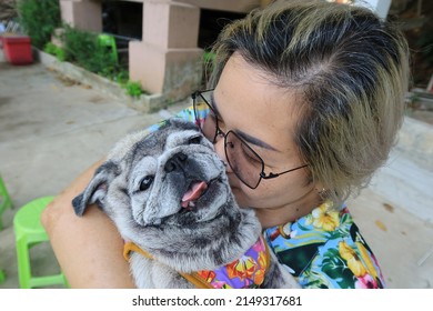 Asian Woman Carrying A Cute Pug Dog With Love.