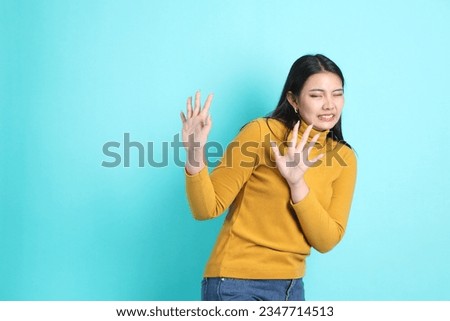 The Asian woman in casual clothes standing on the green background.