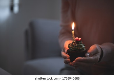 Asian Woman Celebrating Birthday Through Video Call Online Virtual Party At Home While Isolated Stay At Home. Hand Holding Cup Cake Light Up Candle