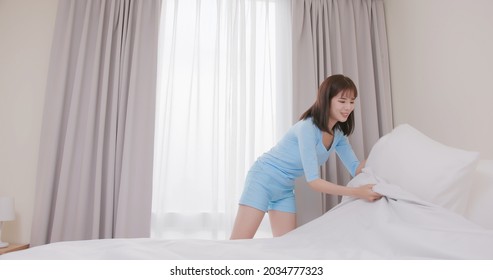 asian woman changes bed sheet with smiling at home