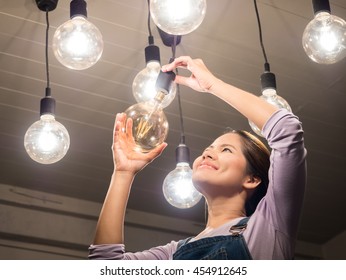 Asian Woman Changing Light Bulb 