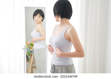 Asian woman checking her shape front of the mirror